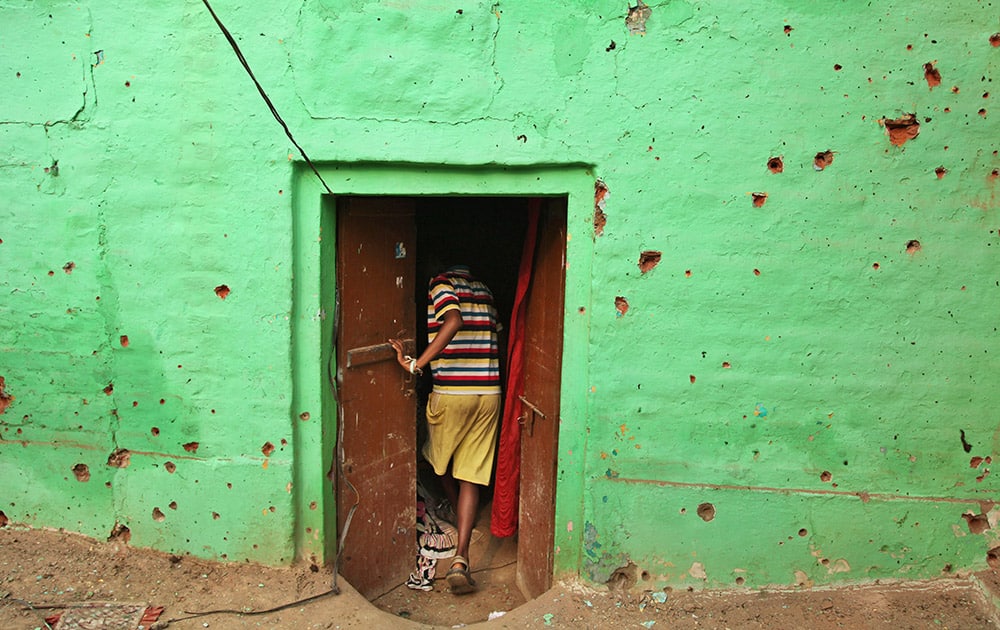 An Indian villager enters a door of his residence near mortar shell marks allegedly fired from the Pakistan's side at Masha da kothe village, in Arnia Sector near the India-Pakistan international border.