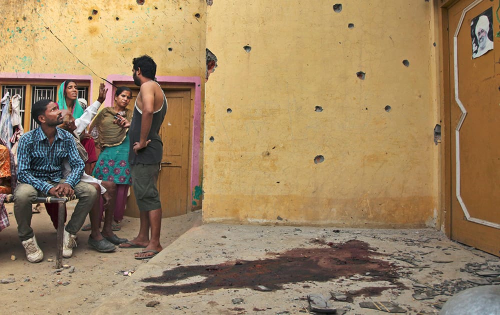 Indian villagers sit near a blood stained spot after alleged mortar shell firing from the Pakistan side into a residential area at Masha da kothe village, in Arnia Sector near the India-Pakistan international border.