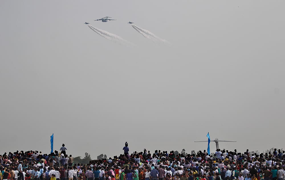 People watch as Indian Air Force's C-17 Globemaster III, center, with Sukhoi Su-30MKI fly during Air Force Day at the air force station in Hindon near New Delhi.