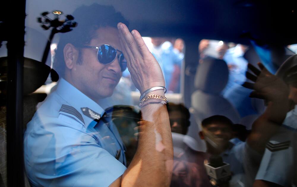 Former Indian cricketer and honorary Indian Air Force Group Captain Sachin Tendulkar waves from a car as he leaves after an Air Force Day parade at the air force station in Hindon near New Delhi.