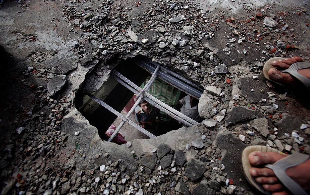 A man looks at a hole in the rooftop of his house, which was made during clashes between Pakistani forces and Indian's in Dhamala Hakimwala village in Pakistan's Punjab province.