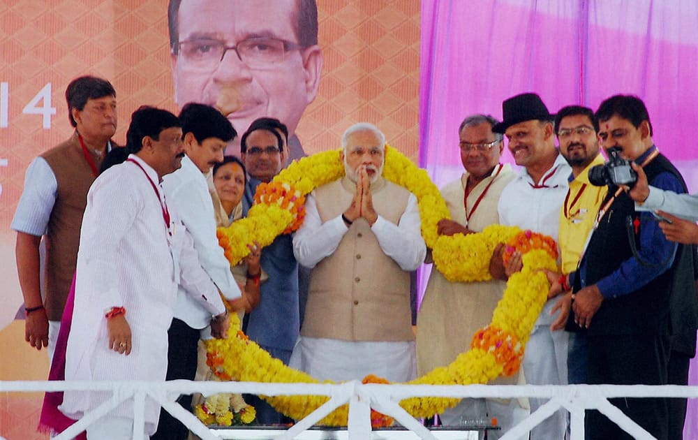 Prime Minister Narendra Modi is garlanded by BJP workers at a party meeting in Indore.