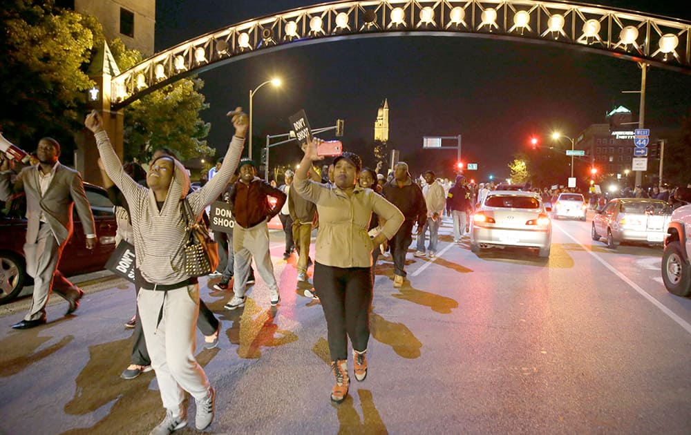 Protesters march down a street blocking traffic, a day after Vonderrit D. Myers was shot and killed by white, off-duty St. Louis police officer in St. Louis. Police say Myers was shot Wednesday after he opened fire on the off-duty officer, but Myers' parents say he was unarmed.