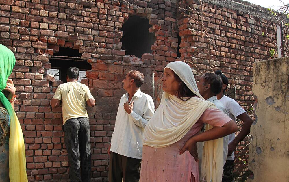 Village women salvage their belongings from one of the houses damaged in firing by Pakistani troops at Village Nanga, in Jammu and Kashmir.