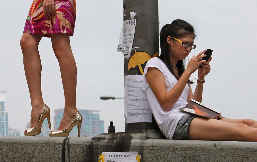A model, poses for a fashion photo shooting as a protester sits on a main road in the occupied areas outside government headquarters in Hong Kong's Admiralty.