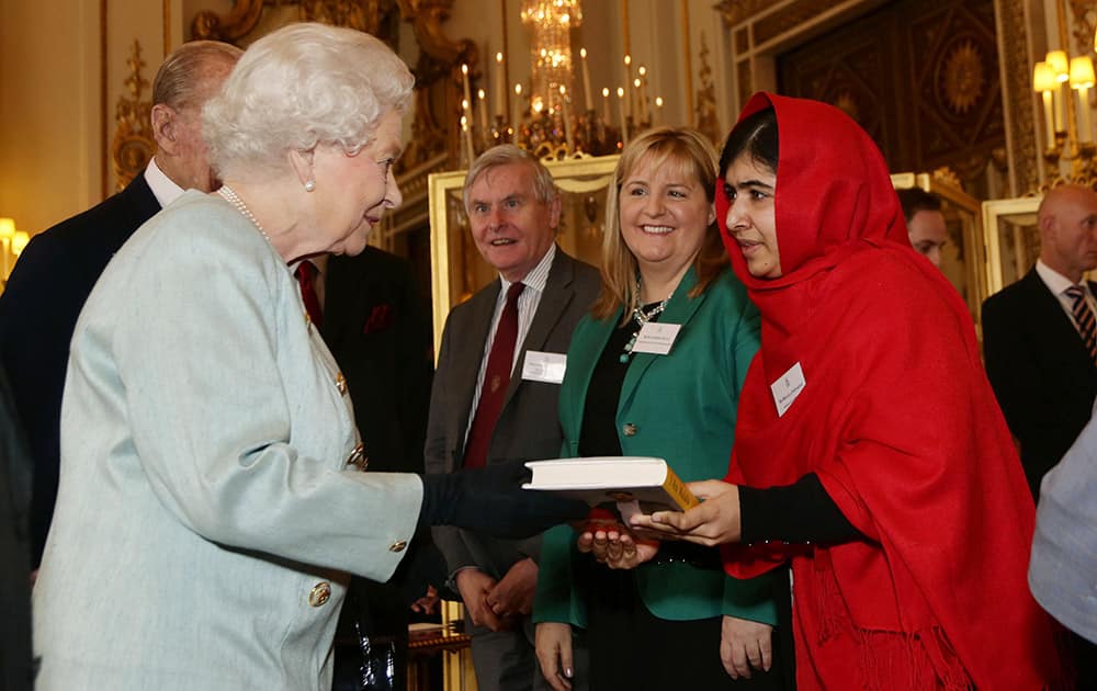 File Photo: Malala Yousafzai gives a copy of her book 'I Am Malala' to Britain's Queen Elizabeth II during a reception for youth, education and the Commonwealth at Buckingham Palace in London. Teenage activist Malala Yousafzai has jointly won the Nobel Peace Prize for her 'heroic struggle' for girls' rights to education, it is announced Friday Oct. 10, 2014.