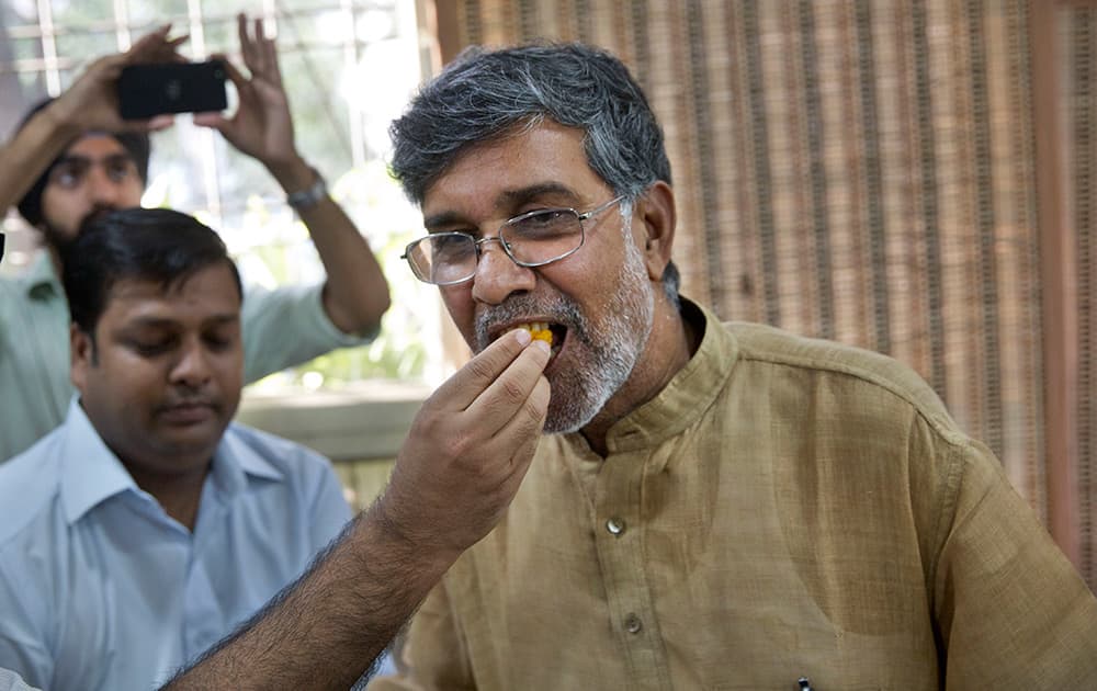 A man offers sweets to children's rights activist Kailash Satyarthi, as they celebrate after Satyarthi won the Nobel Peace Prize, at his office in New Delhi. Malala Yousafzai of Pakistan and Satyarthi of India jointly won the Nobel Peace Prize for risking their lives to fight for children's rights.