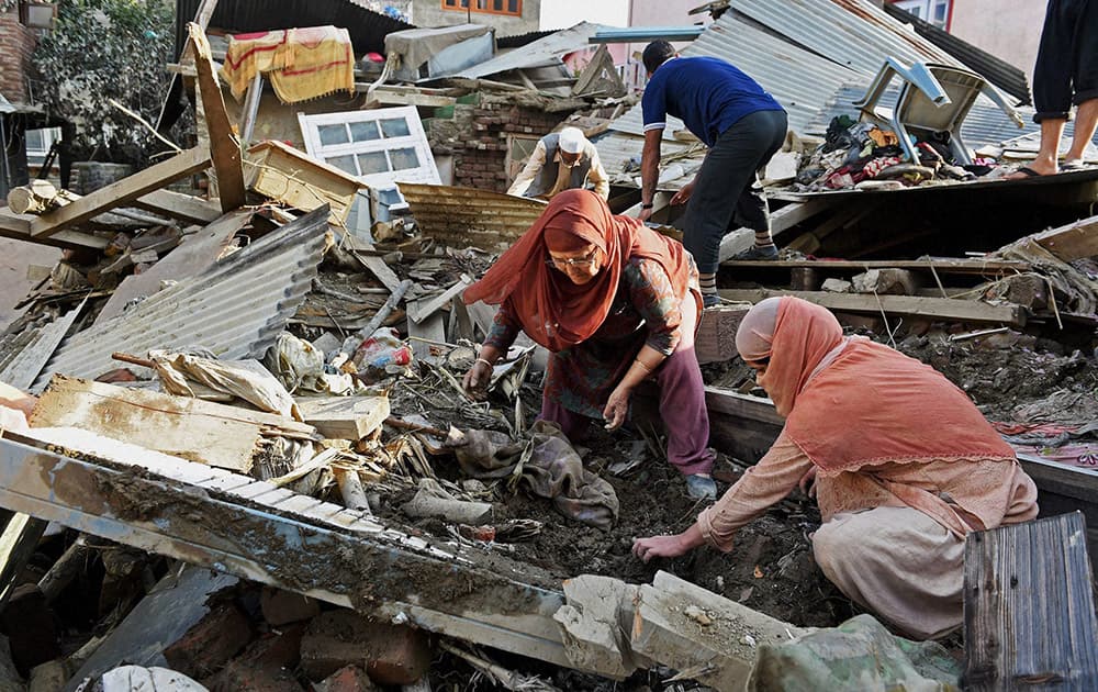 Flood victims salvage their belongings at their collapsed house in Srinagar.