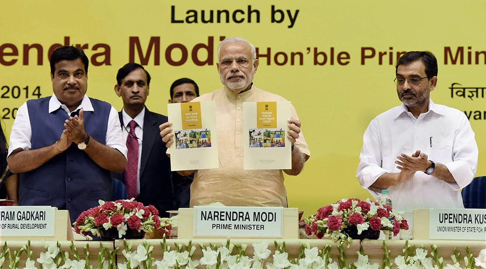 Prime Minister Narendra Modi launches the Saansad Adarsh Gram Yojana (SAGY) as Union Minister for Rural Development Nitin Gadkari and Minister of State for Rural Development Upendra Khushwa clap in New Delhi.