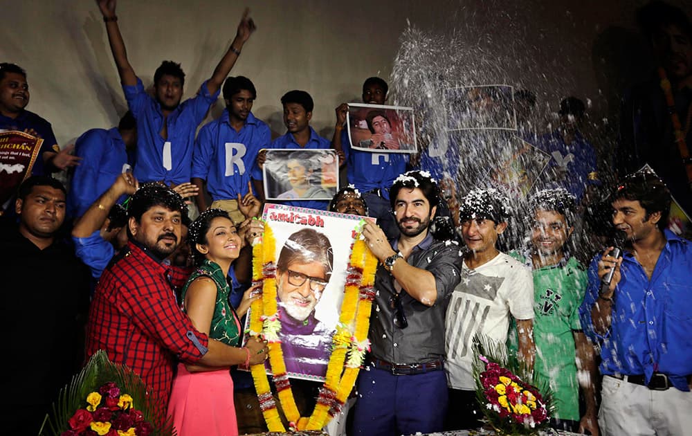 Bollywood actors Jeet, fourth right, and Aindrita, second left, hold a portrait of actor Amitabh Bachchan as they celebrate his 72nd birth anniversary with his fan-club, in Kolkata.