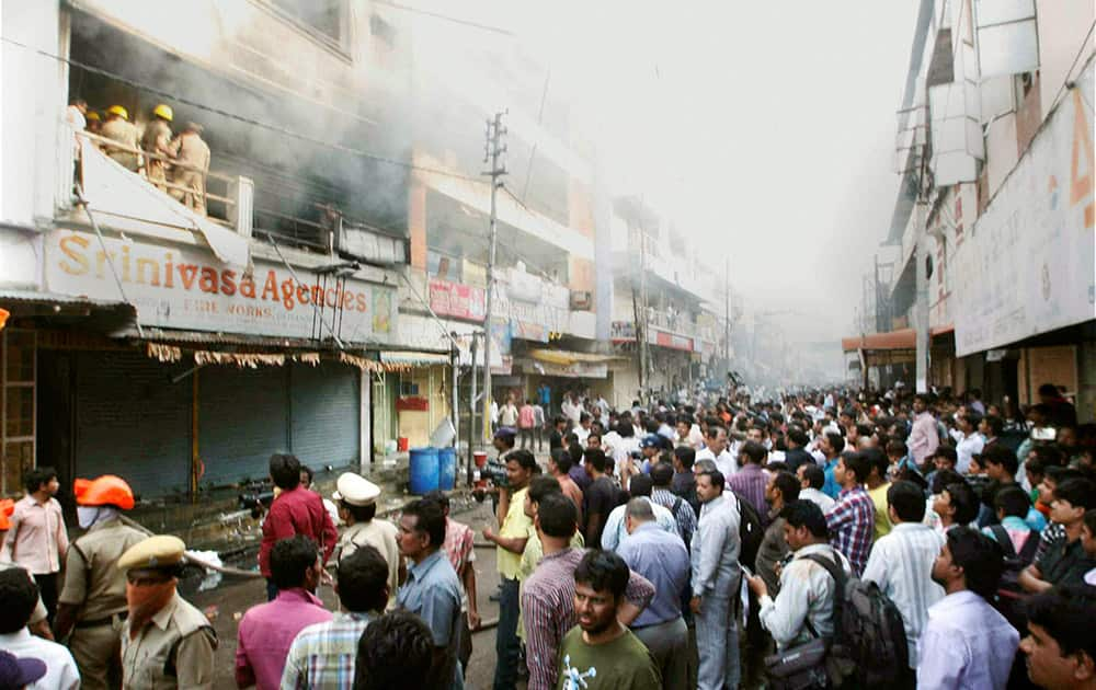 People watch as fire men douse a fire that broke out at a shopping complex in Hyderabad.