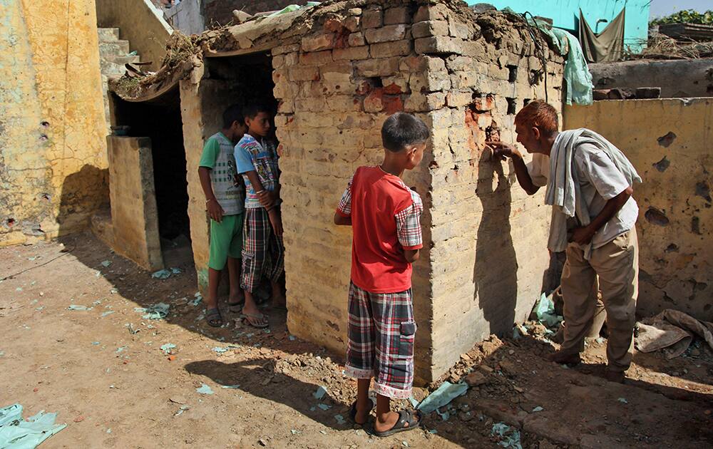 A village man looks at one of the houses damaged in firing between India and Pakistan at the border area of Treava village in Arnia sector, in Jammu.