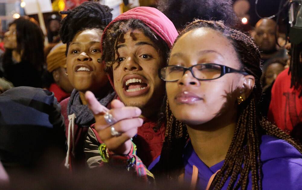 Protesters yell at a black law enforcement officer during a protest at the Ferguson Police Department in Ferguson, Mo. 