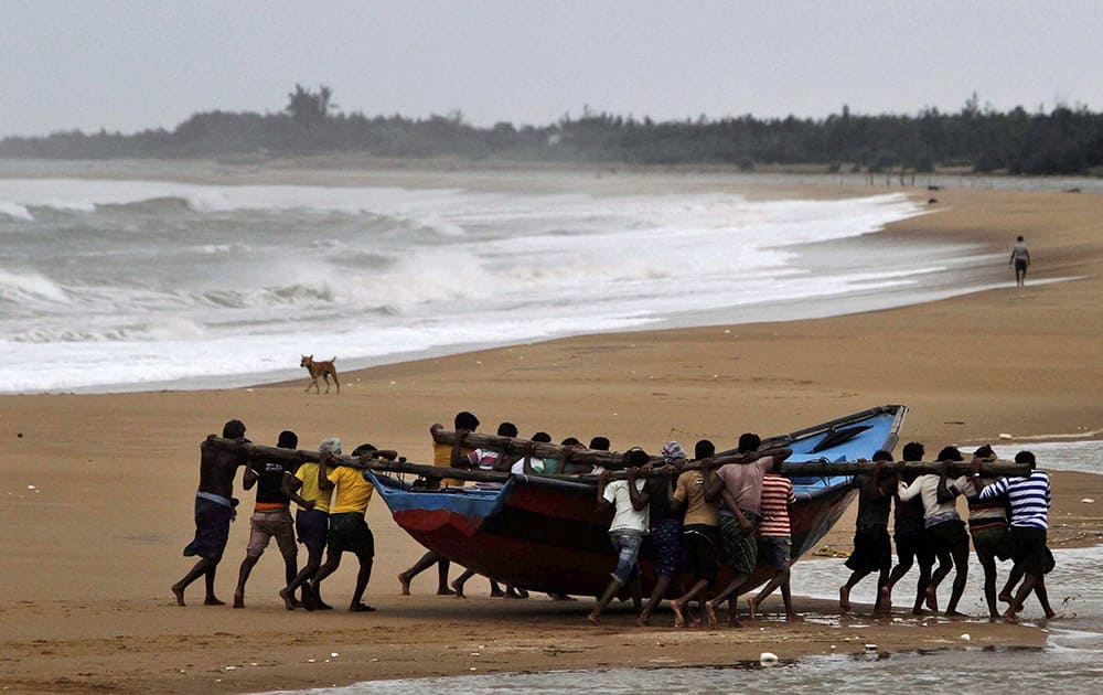 Fishermen move a boat away from the coast following cyclone Hudhud warning near Podampeta village in Ganjam district.