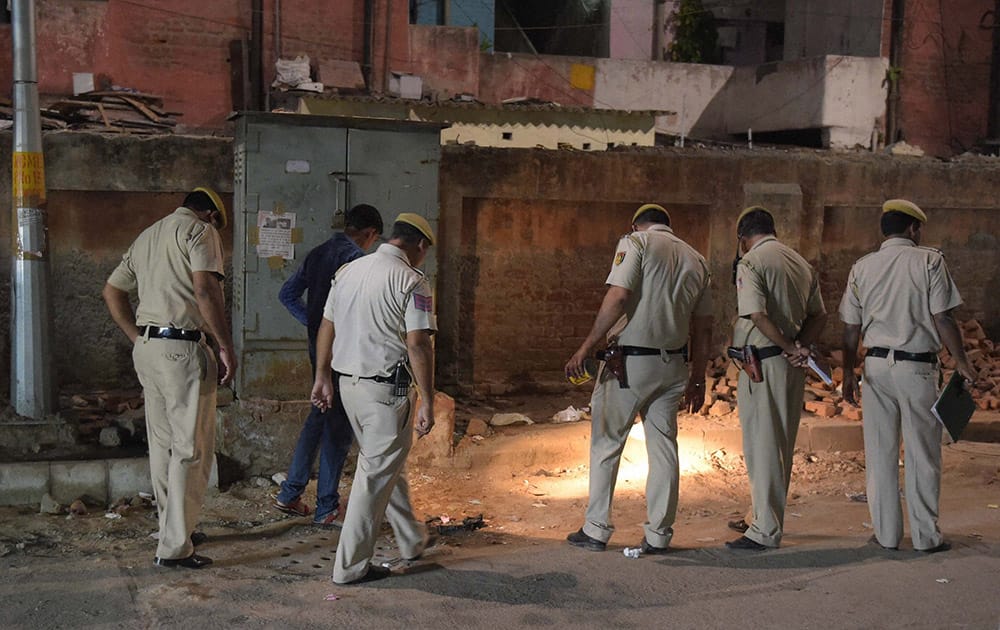 Delhi police officials search a spot after unidentified men allegedly fired shots in Connaught Place, in New Delhi.