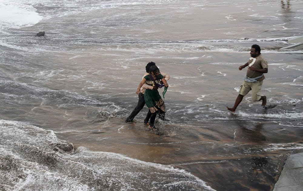 A man, right, rushes to help as another rescues a woman who fell due to strong tidal waves on the Bay of Bengal coast at Gopalpur, Orissa, about 285 kilometers (178 miles) north east of Visakhapatnam, India.