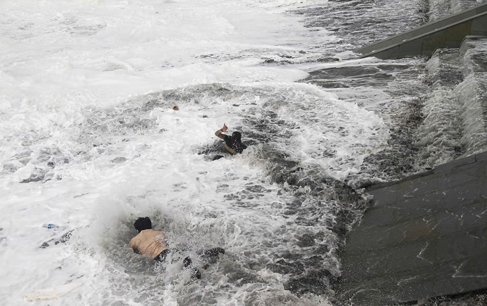 A man, bottom jumps into the water to rescue a woman, center, who fell due to strong tidal waves on the Bay of Bengal coast at Gopalpur, Orissa, about 285 kilometers (178 miles) north east of Visakhapatnam, India.