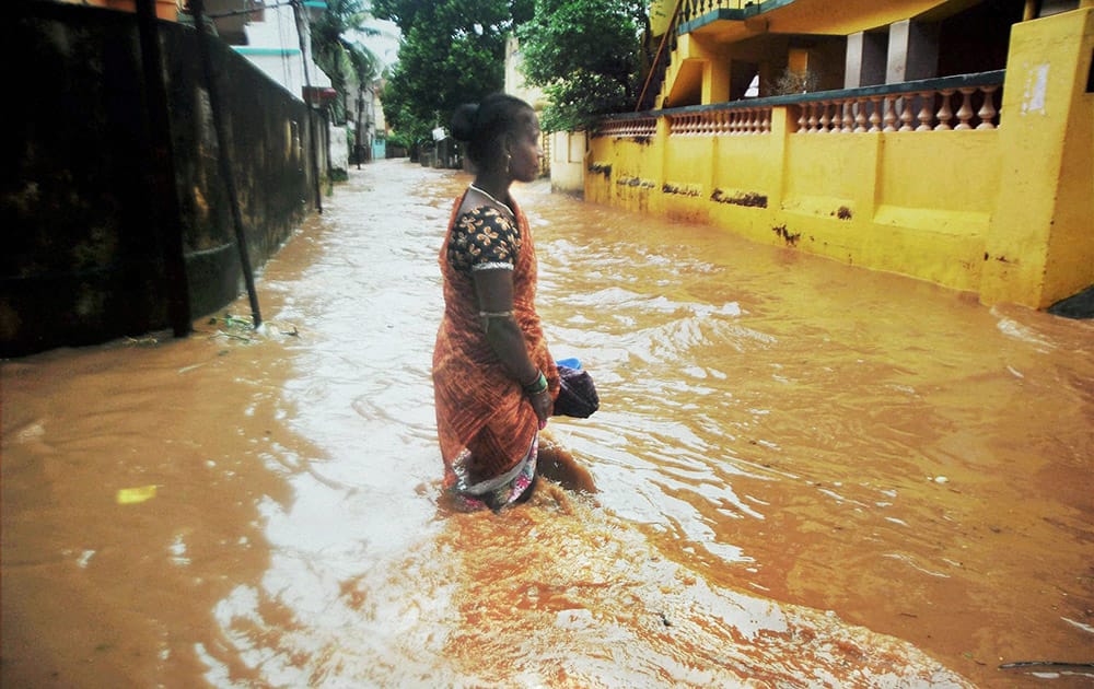 A woman wades through a water logged street after cyclone Hudhud caused heavy rains in Bhubaneswar.