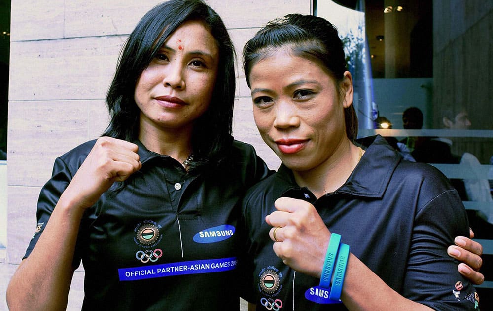 Boxers Mary Kom and L Sarita Devi pose for photographs during a felicitation function organised by Samsung for the medal winners of recent Asian Games, in New Delhi.