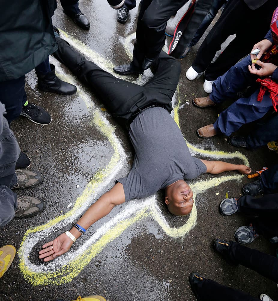 Pastor Charles Burton lies on the driveway at the Ferguson, Mo., police station as a chalk drawing is made as a memorial to Michael Brown.