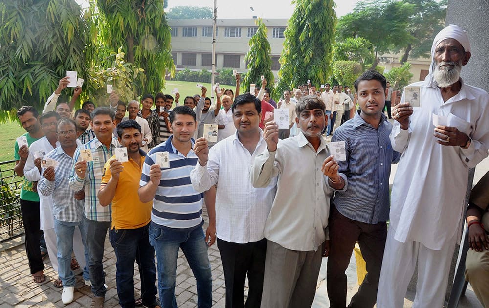 People wait in a long queue to cast votes for Assembly polls, at a polling station in Sonipat.