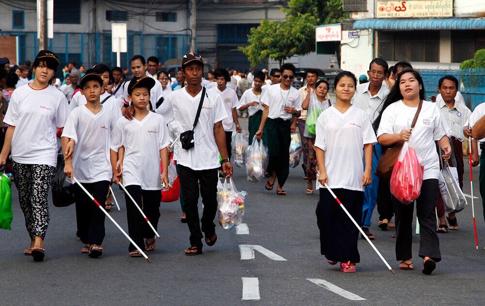 Visually impaired people walk with white canes during the annual White Cane Day Walk in downtown Yangon, Myanmar.