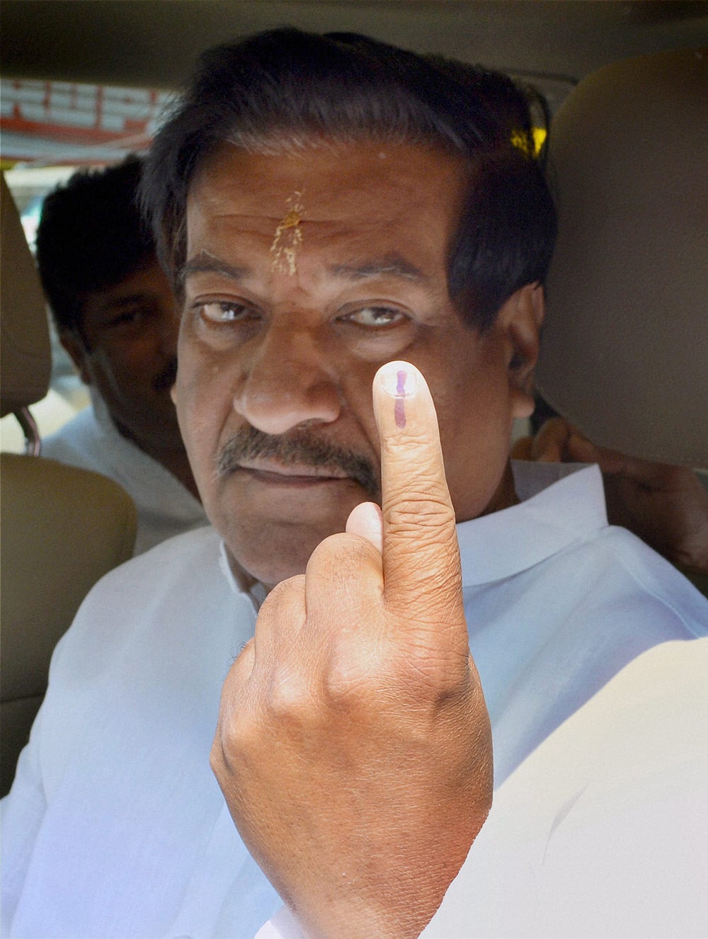 Former Maharashtra Chief Minister Prithviraj Chavan shows his inked finger after casting his vote in the Assembly elections in Karad.