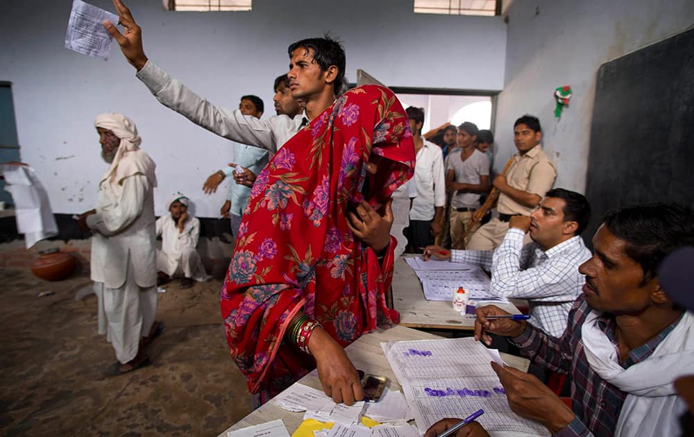 A woman dips her thumb in ink to give a thumb imprint at a polling station during the Haryana state elections in Nuh.