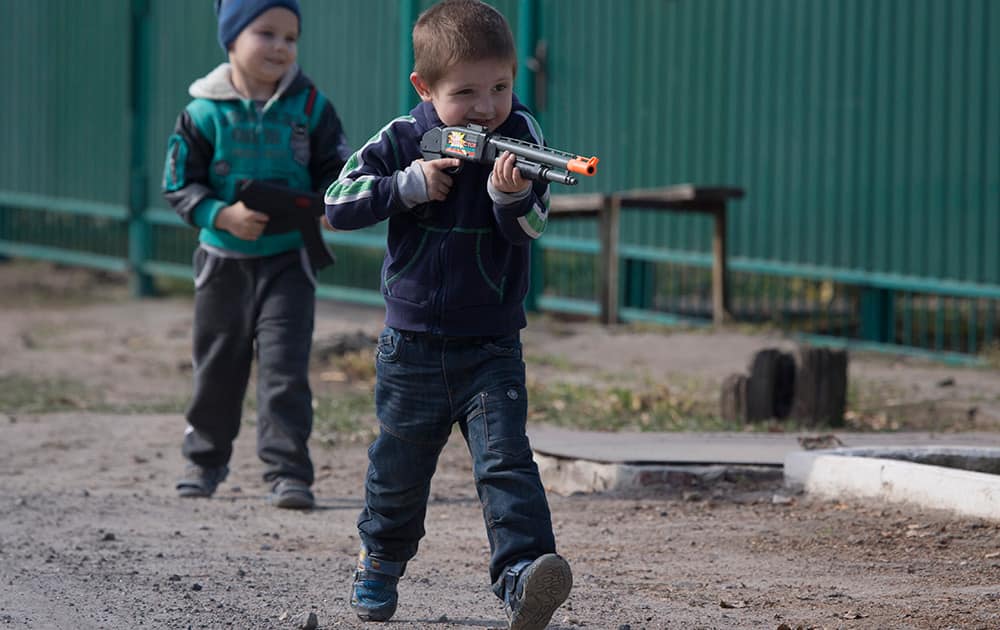 Boys play with toy guns near to the area where shelling landed killing several people in Sartana village, on the outskirts of the town of Mariupol, eastern Ukraine .