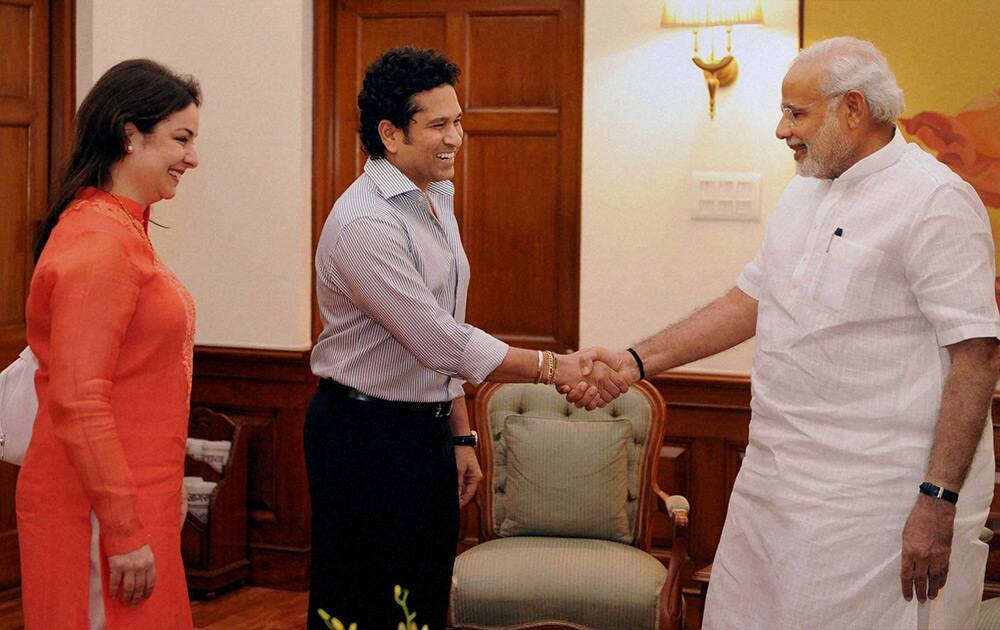 Prime Minister Narendra Modi shakes hands with cricket legend Sachin Tendulkar as his wife Anjali looks on at a meeting in New Delhi.