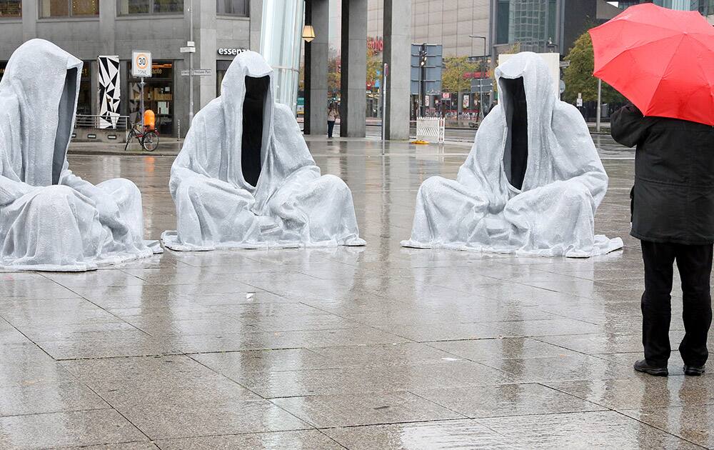 A man stands in front of the installation 'Waechter der Zeit' ('guardians of time') at Potsdamer Platz in Berlin, Germany.