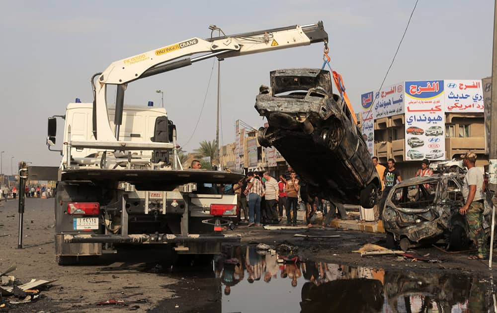 A tow truck lifts a destroyed vehicle from the site of a car bomb explosion in the largely Shiite eastern neighborhood of Talibiyah in Baghdad, Iraq.