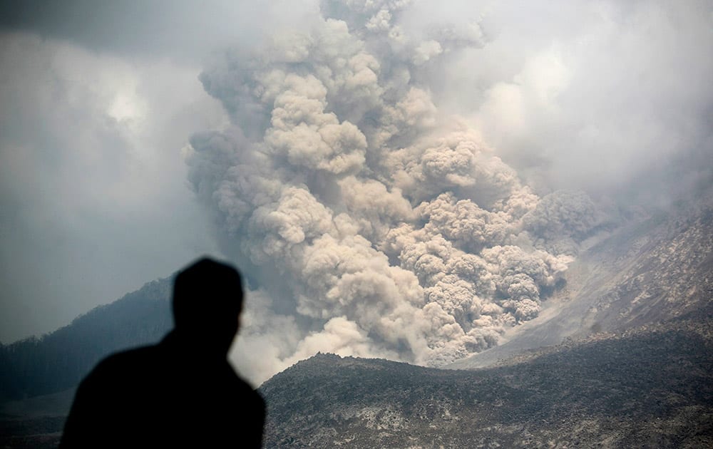 An Indonesian man watches as a pyroclastic flow sweeps down the slope of Mount Sinabung in Tiga Serangkai, North Sumatra, Indonesia.