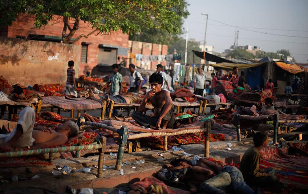 An Indian squatter smokes as others sleep on rented cots at a public park near Jama Masjid, or the Grand Mosque, in New Delhi.