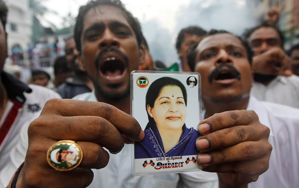 A supporter holds a portrait of former chief minister of Tamil Nadu state Jayaram Jayalalitha, a former movie star, as he celebrates with others news of bail being granted to their leader, outside their party office in Chennai.