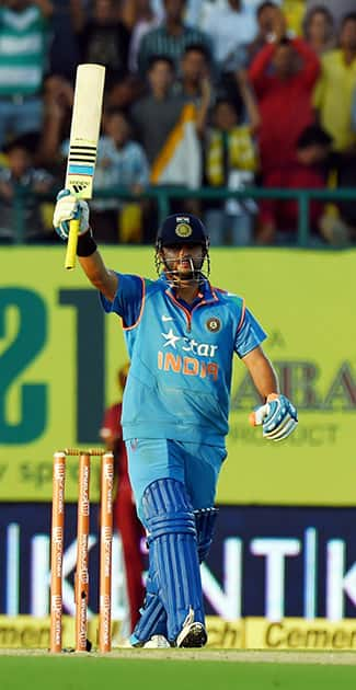 Suresh Raina raises his bat after completing his half century during the India- West Indies ODI match, in Dharamshala.