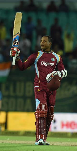 West Indies batsman Samuels raises his bat on completing his century during the India-West Indies ODI match in Dharamshala.