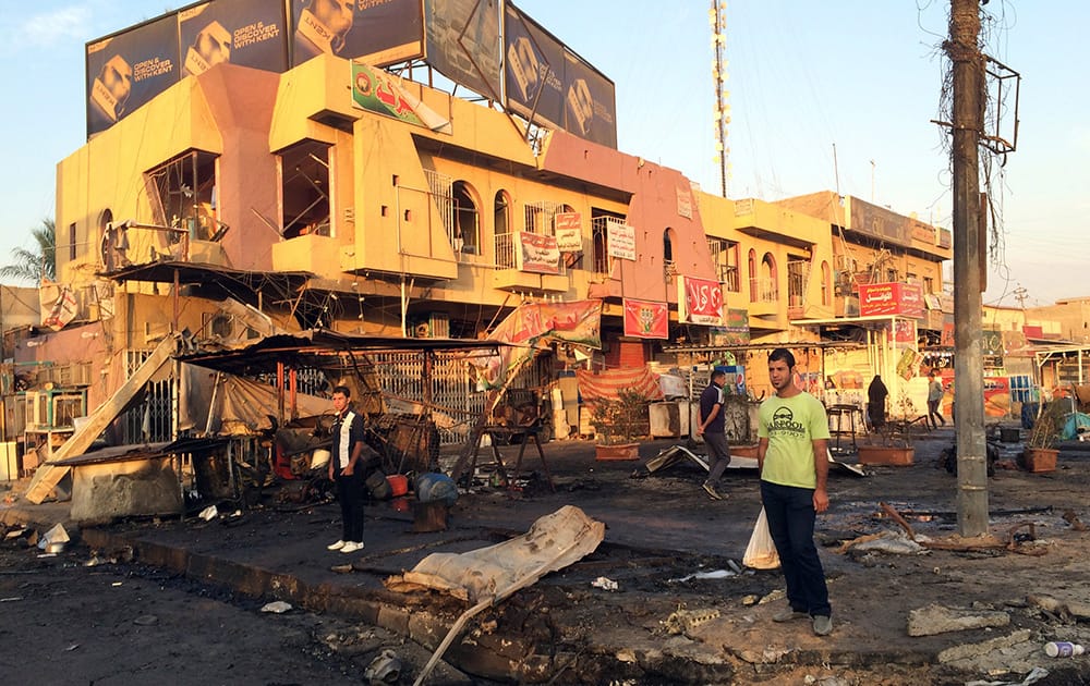 Civilians inspect the aftermath of a car bomb explosion in the morning in Baghdad's eastern neighborhood of Baladiyat, Iraq.