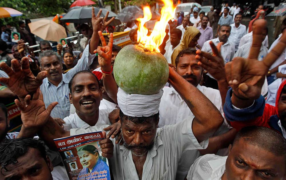 A supporter of former chief minister of Tamil Nadu state Jayaram Jayalalitha carries a burning pumpkin, a ritual to drive away evil, as he waits with others to greet their leader outside her residence after she was released from a Bangalore prison in Chennai, India.