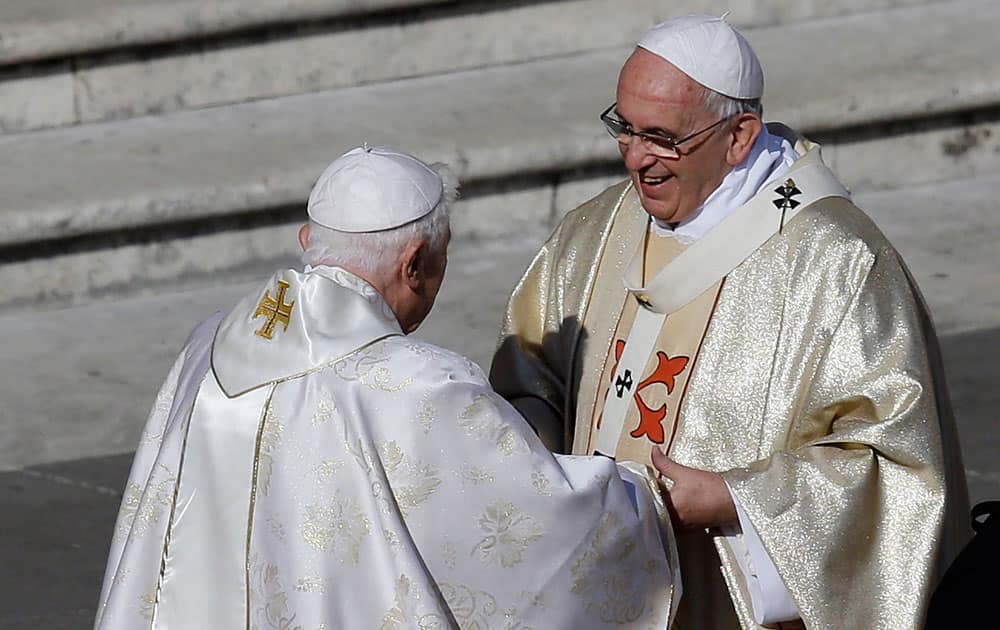 Pope Emeritus Benedict XVI, left, greets Pope Francis prior to the start of the beatification ceremony of Pope Paul VI and a mass for the closing of a two-week synod on family issues, in Saint Peter's Square at the Vatican.