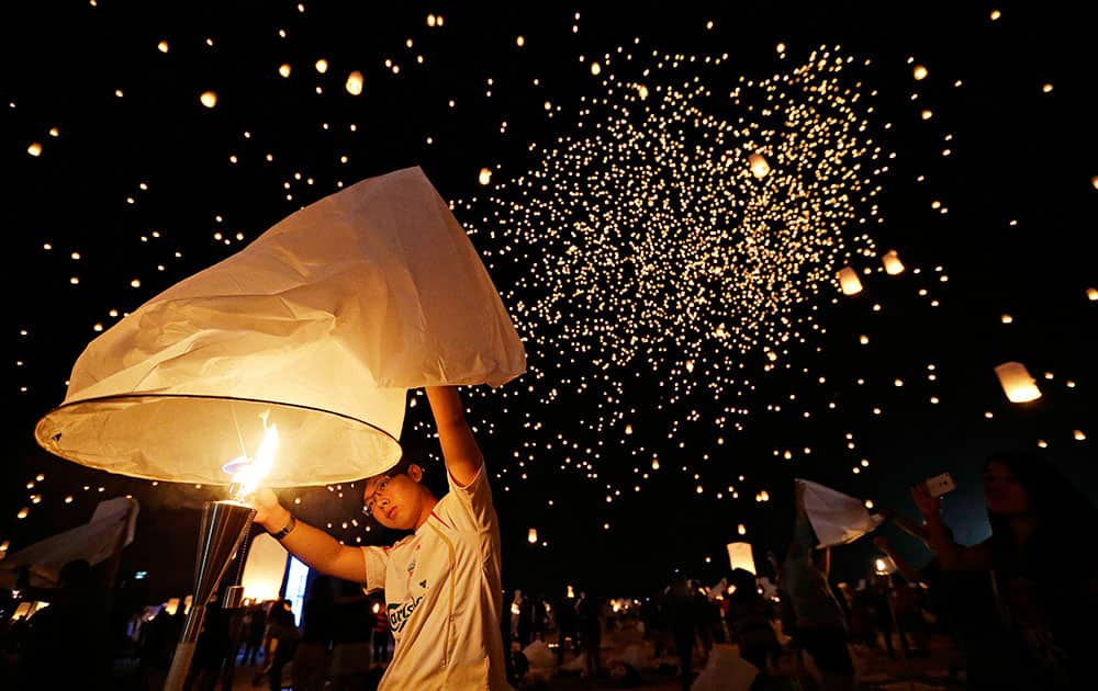 A man holds up a paper lantern before letting it float away at the RiSE Festival near Jean, Nev. Thousands of people attended the festival and released paper lanterns into the sky.