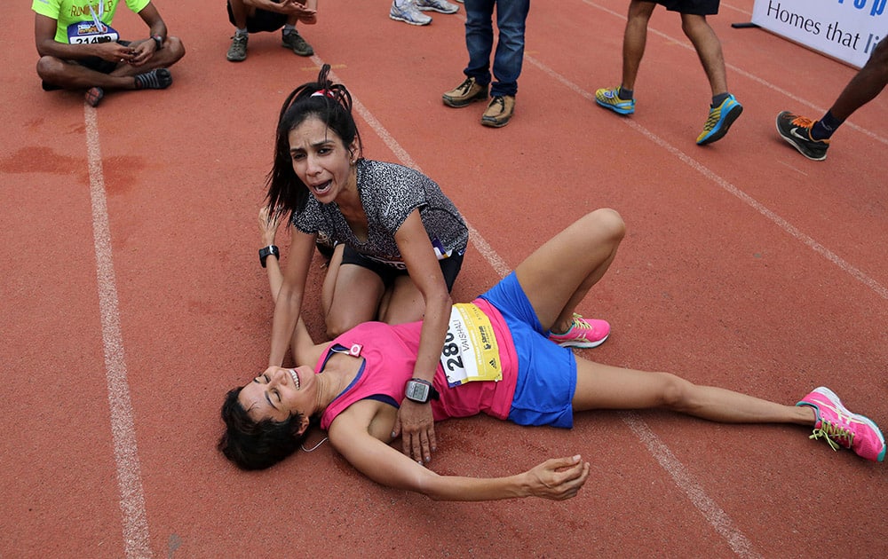 Two among the participants prepare to embrace each other as they celebrate after crossing the finishing line during the Bengaluru Marathon in Bangalore.