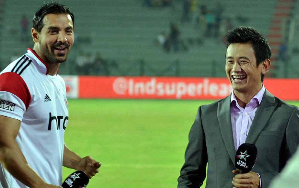 John Abraham, co-owner of North East United Football Club with former Indian Football player Bhaichung Bhutia shares a light moment during the ISL match against Goa FC, at Indira Gandhi Athletic Stadium in Guwahati.