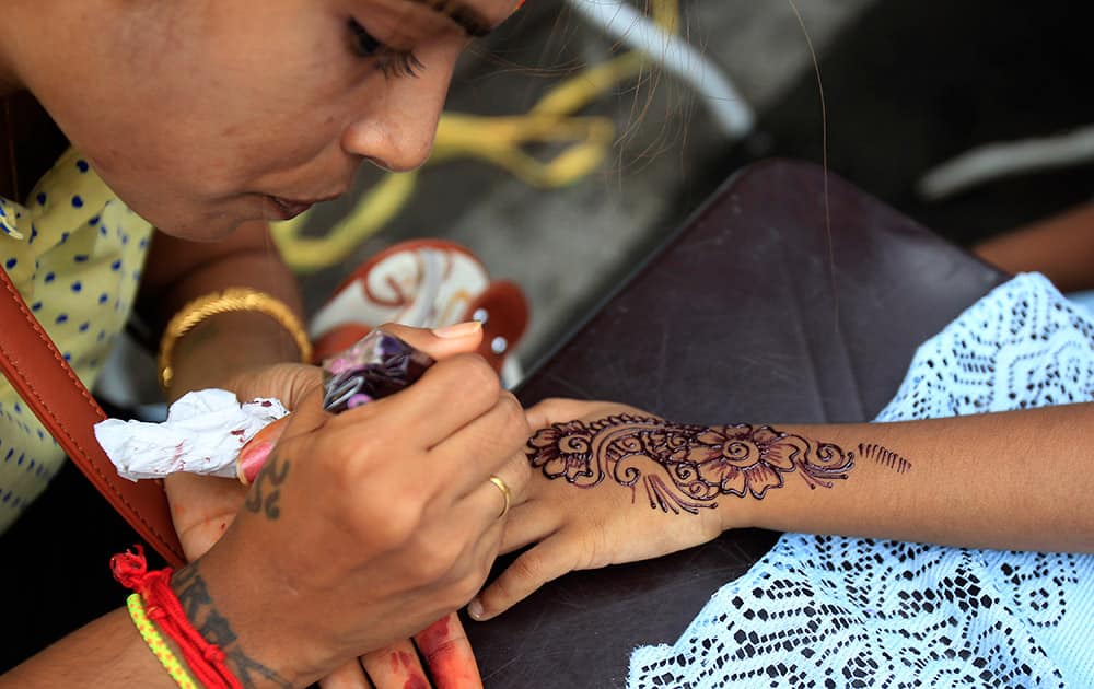 An artist applies henna on the hand of a Malaysian ethnic Indian girl for the upcoming Diwali, or the Hindu festival of lights in Klang, outside Kuala Lumpur, Malaysia.