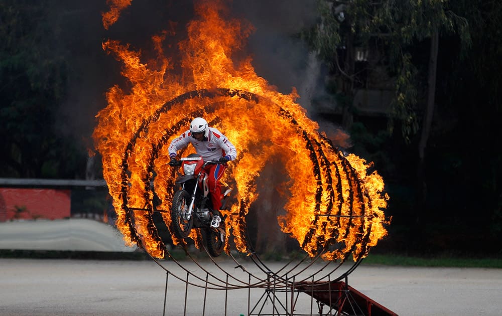 A member of Shwet Ashw, the motorcycle display team of the Indian army, jumps through a fire ring as he performs a daredevil stunt during the platinum jubilee celebrations of Corps of Military Police in Bangalore.