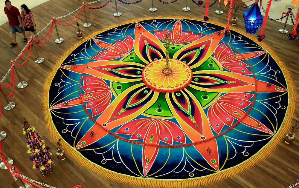 Shoppers walk past an Indian traditional creative artwork `Kolam,` a form of sandpainting, for the upcoming Diwali, or the Hindu festival of lights.