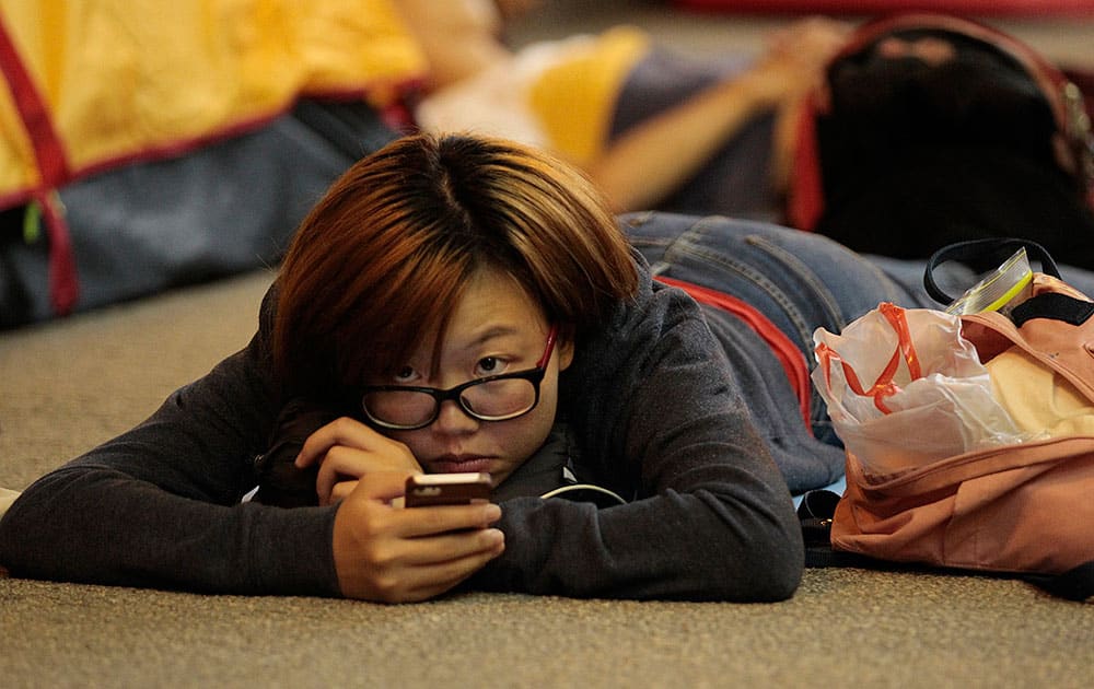 A pro-democracy student protester looks up from her smart phone at the protest site in the Mong Kok district of Hong Kong.