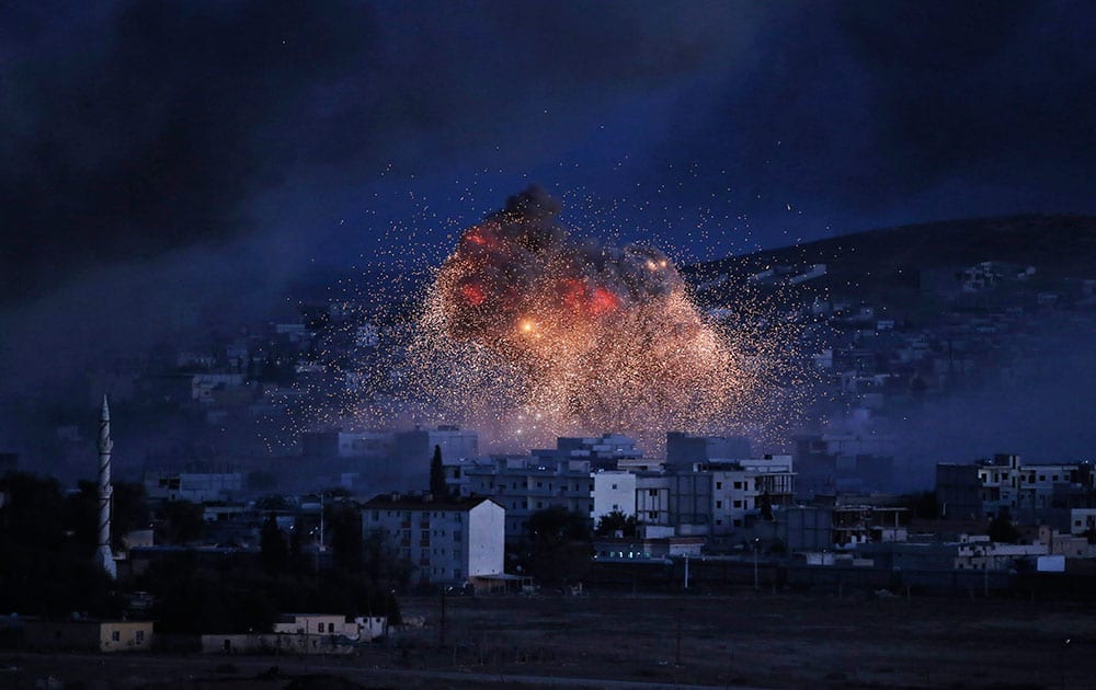 Smoke and flames from an airstrike by the US-led coalition rise in Kobani, Syria, as seen from a hilltop on the outskirts of Suruc, at the Turkey-Syria border, Kobani, also known as Ayn Arab, and its surrounding areas, has been under assault by extremists of the Islamic State group since mid-September and is being defended by Kurdish fighters.