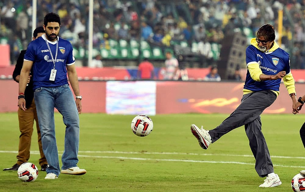 Bollywood Actor Amitabh Bachchan kicks a football as Chennaiyin FC co owner Abhishek Bachchan looks on during the Indian Super League match between Chennaiyin FC and Kerala Blasters FC in Chennai.