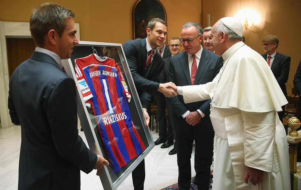 Karl-Heinz Rummenigge, CEO of FC Bayern Muenchen presents a gift with his players Manuel Neuer, second left, and Philipp Lahm, left, for Pope Francis during a private audience in the Palace of the Vatican, in Vatican City. 